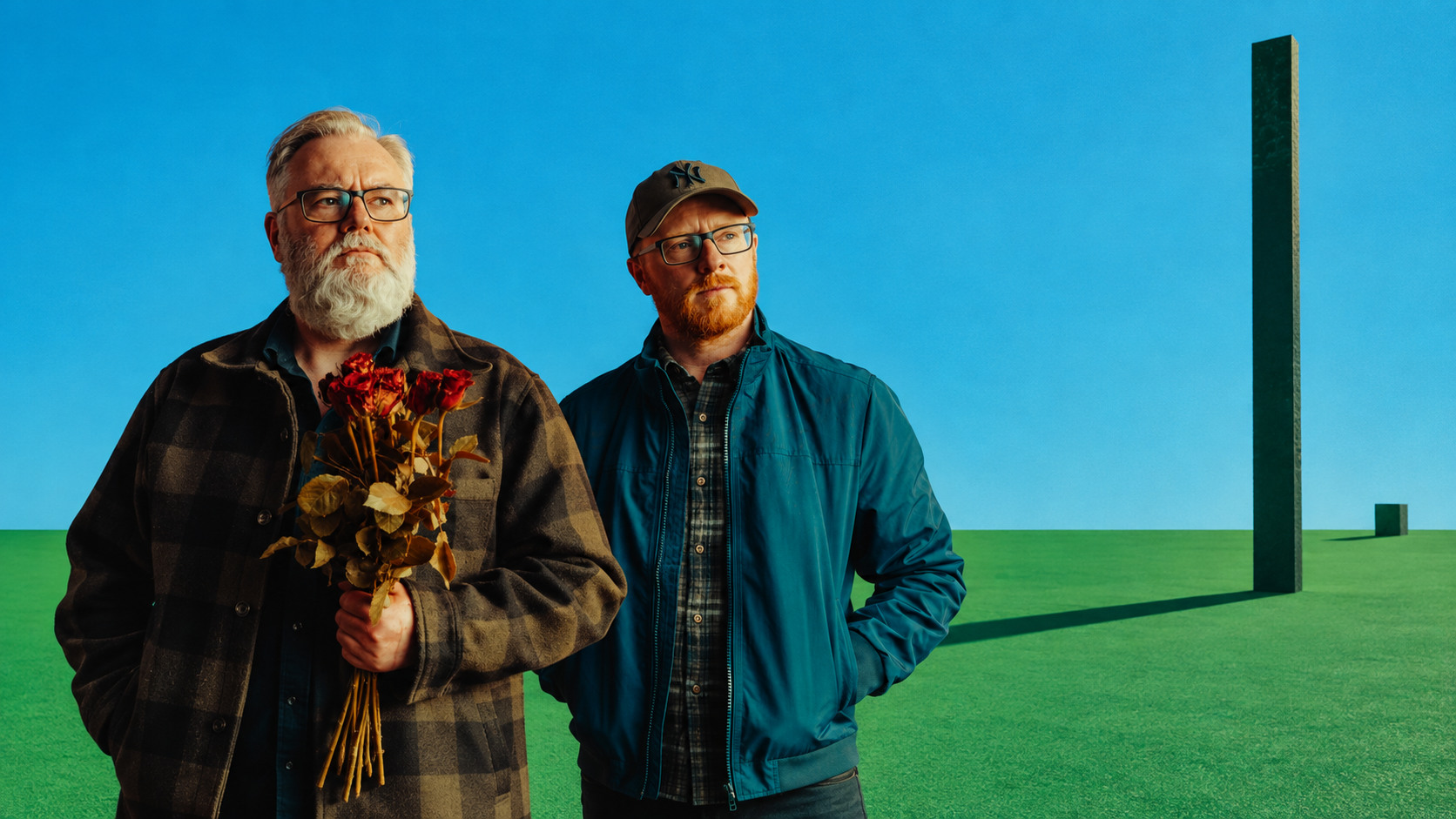 Arab Strap dans un paysage minimaliste bleu et vert, Aidan Moffat tenant un bouquet de roses aux côtés de Malcolm Middleton.