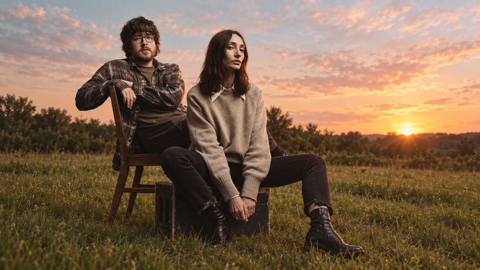 King Hannah dans un champ au coucher du soleil, Hannah Merrick au premier plan et Craig Whittle assis derrière elle.