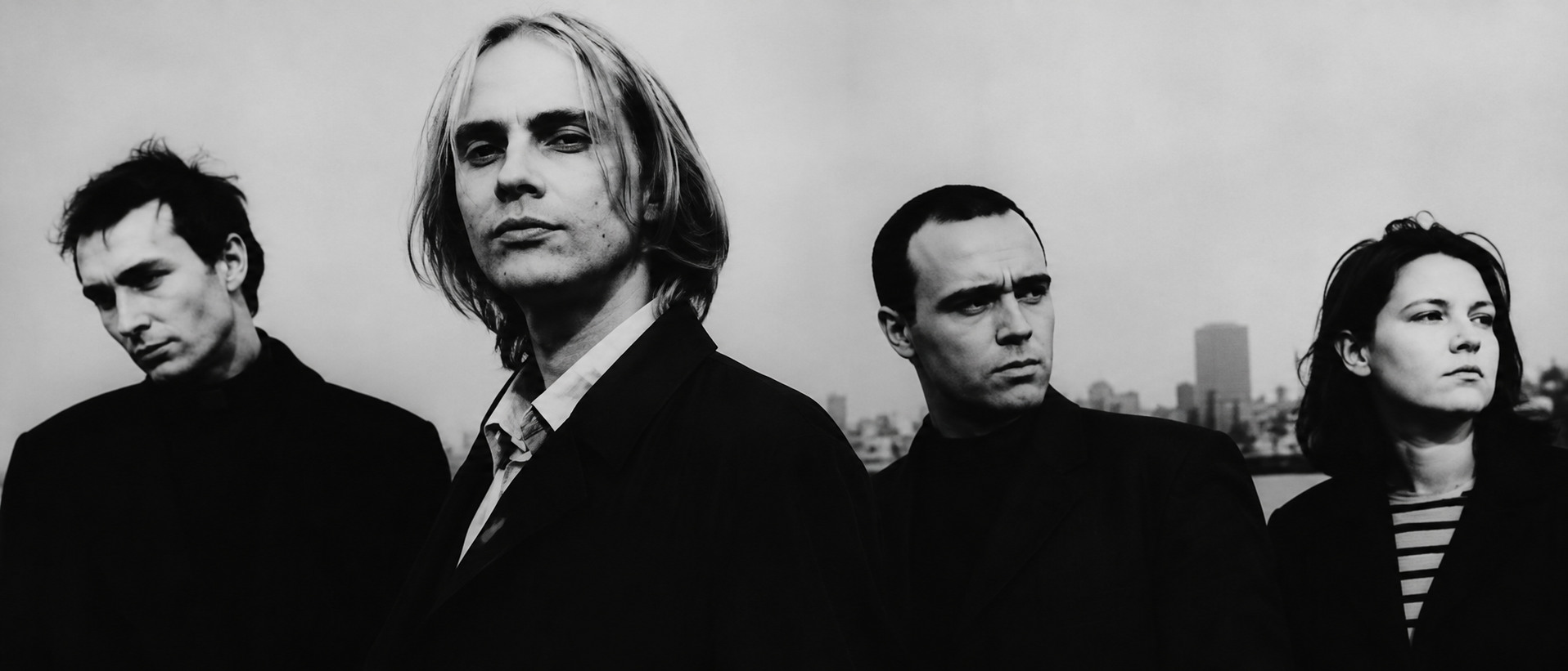 The Auteurs, portrait de groupe en noir et blanc devant un horizon urbain.