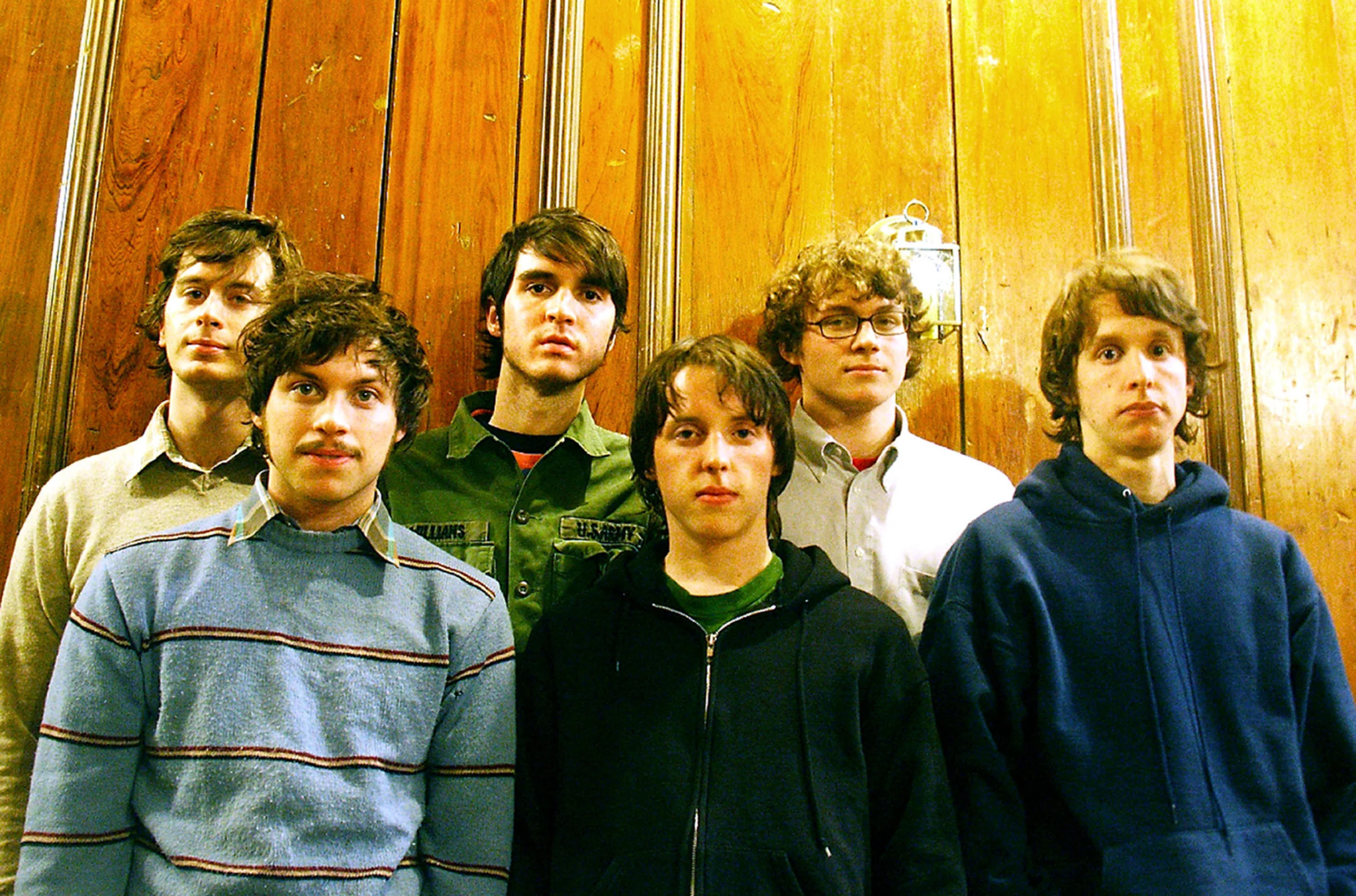 The Spinto Band devant un mur lambrissé, portrait de groupe.